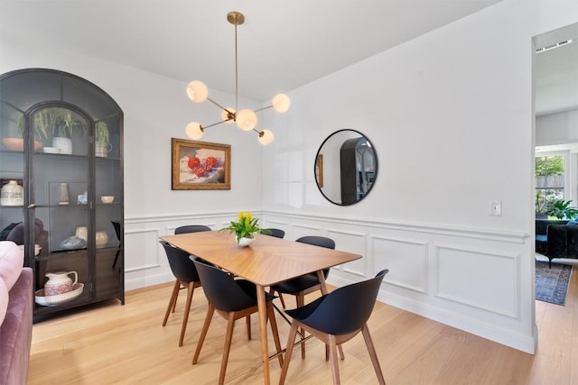 1105 Red Ranch Cir, Cedar Park, TX 78613 - dining room with light wood finished floors, a decorative wall, a chandelier, and wainscoting