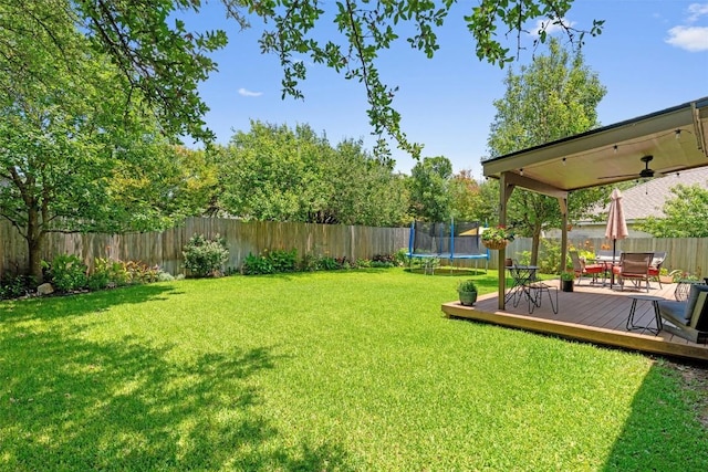 1105 Red Ranch Cir, Cedar Park, TX 78613 - fenced backyard with a trampoline, a wooden deck, outdoor dining space, and ceiling fan