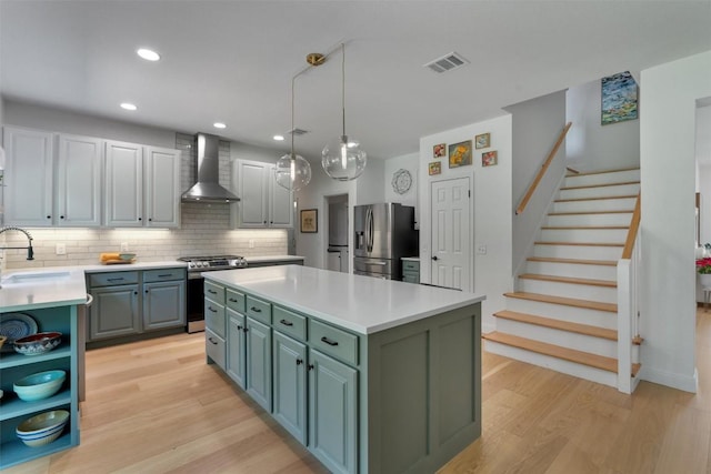 1105 Red Ranch Cir, Cedar Park, TX 78613 - kitchen featuring appliances with stainless steel finishes, wall chimney exhaust hood, light wood finished floors, green cabinetry, and light countertops