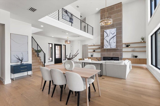 1000 Southlake Ranch Rd, Georgetown, TX 78628 - dining space with stairway, a towering ceiling, a chandelier, light wood-style flooring, and a tiled fireplace