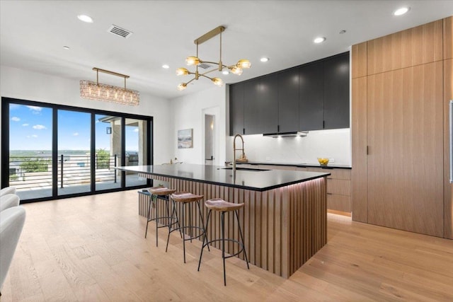 1000 Southlake Ranch Rd, Georgetown, TX 78628 - kitchen featuring light wood finished floors, dark cabinets, dark countertops, a breakfast bar, and recessed lighting