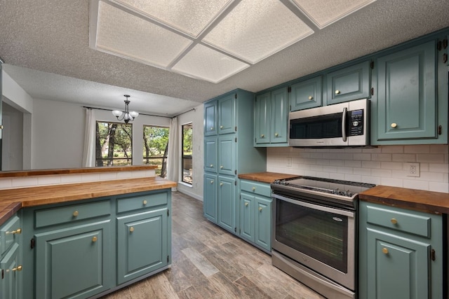 216 Country Rd, Georgetown, TX 78628 - kitchen with wood counters, stainless steel appliances, a chandelier, light wood-style floors, and tasteful backsplash