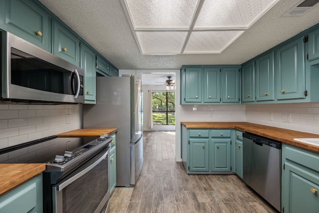 216 Country Rd, Georgetown, TX 78628 - kitchen with appliances with stainless steel finishes, butcher block countertops, light wood-type flooring, decorative backsplash, and a textured ceiling