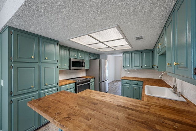 216 Country Rd, Georgetown, TX 78628 - kitchen featuring appliances with stainless steel finishes, butcher block counters, a textured ceiling, backsplash, and a peninsula