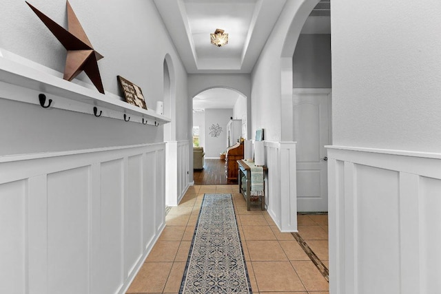 1008 Tabernash Dr, Leander, TX 78641 - hall with arched walkways, light tile patterned floors, a wainscoted wall, a decorative wall, and a raised ceiling