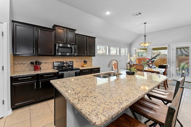 1008 Tabernash Dr, Leander, TX 78641 - kitchen featuring stainless steel microwave, electric range, light stone countertops, a kitchen breakfast bar, and decorative backsplash