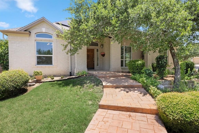9601 Billingham Trl, Austin, TX 78717 - view of front of property featuring roof mounted solar panels, a front lawn, and brick siding