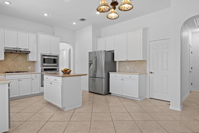 9601 Billingham Trl, Austin, TX 78717 - kitchen with stainless steel appliances, arched walkways, under cabinet range hood, light tile patterned floors, and recessed lighting