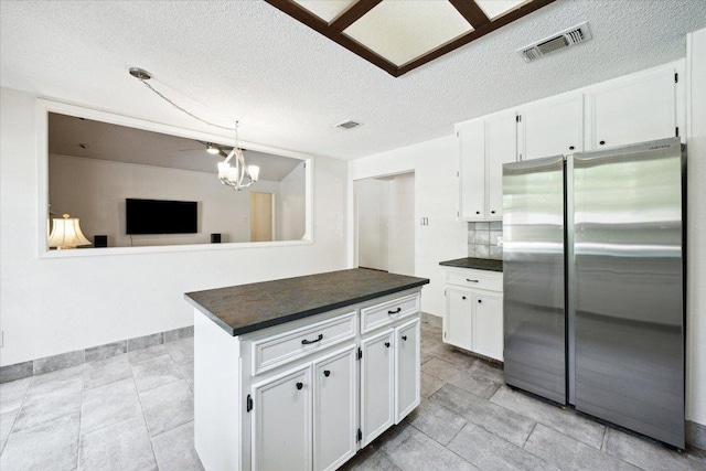 9902 Marseilles Dr, Austin, TX 78750 - kitchen with freestanding refrigerator, dark countertops, white cabinetry, a textured ceiling, and a chandelier