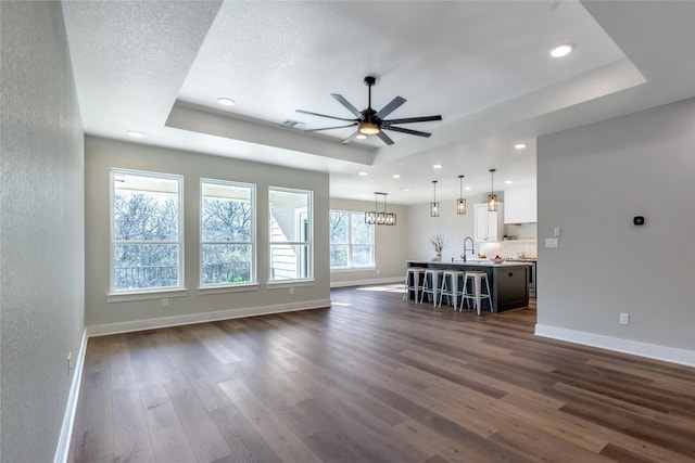 1720 Cannon St, Gonzales, TX 78629 - unfurnished living room featuring a tray ceiling, dark wood-type flooring, recessed lighting, and a ceiling fan