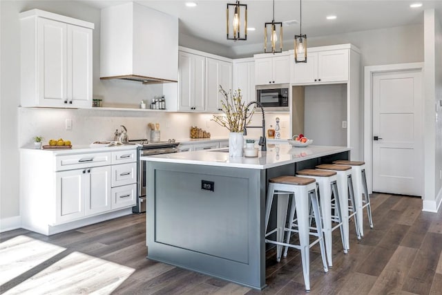 1720 Cannon St, Gonzales, TX 78629 - kitchen with appliances with stainless steel finishes, recessed lighting, white cabinetry, dark wood-style flooring, and a center island with sink