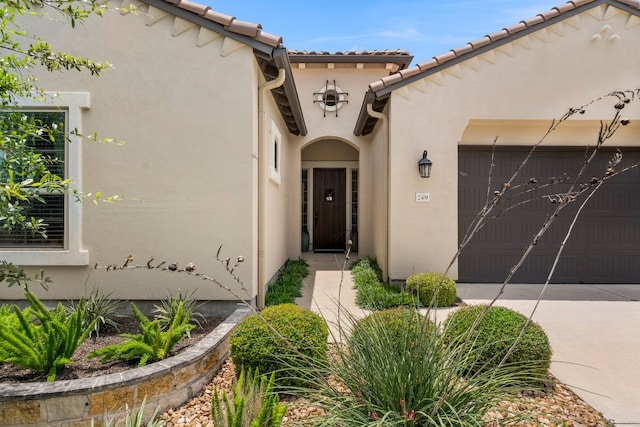 249 Hopping Peach St, San Marcos, TX 78666 - property entrance featuring a garage, stucco siding, concrete driveway, and a tiled roof