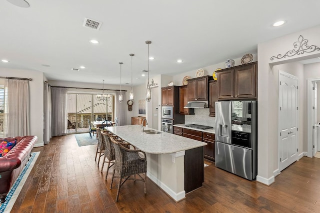 249 Hopping Peach St, San Marcos, TX 78666 - kitchen with stainless steel appliances, under cabinet range hood, a kitchen breakfast bar, dark wood-style floors, and recessed lighting