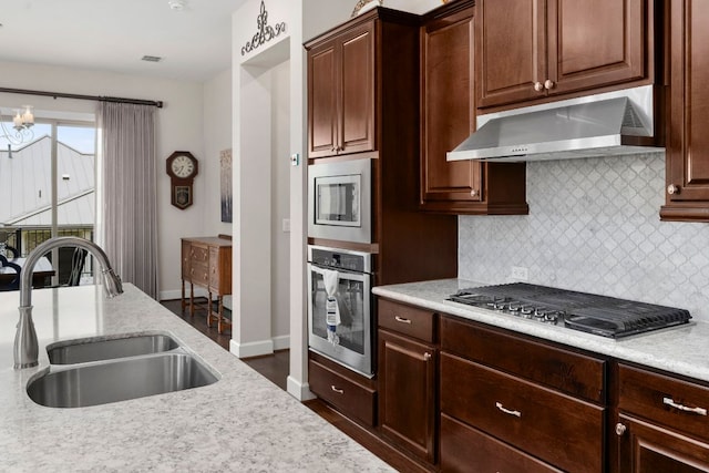 249 Hopping Peach St, San Marcos, TX 78666 - kitchen with stainless steel appliances, exhaust hood, decorative backsplash, dark wood-type flooring, and light stone counters