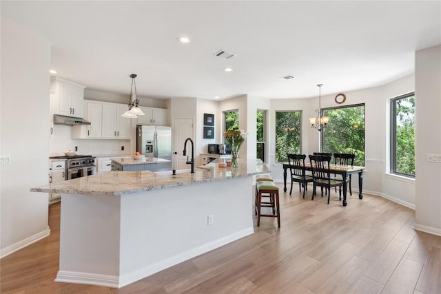 10636 Bramblecrest Dr, Austin, TX 78726 - kitchen with stainless steel appliances, a large island with sink, under cabinet range hood, light wood-style floors, and recessed lighting