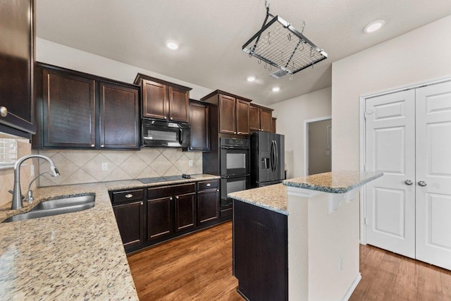 3303 Lorne Dr, Killeen, TX 76542 - kitchen with black appliances, wood finished floors, a kitchen island, decorative backsplash, and recessed lighting
