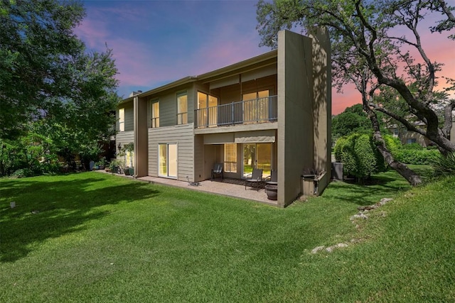 230 Lido St Unit I-2, Lakeway, TX 78734 - back of house at dusk featuring a balcony, a lawn, and a patio