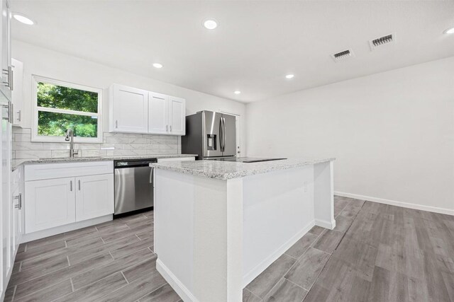 605 W Washington Ave, Copperas Cove, TX 76522 - kitchen with stainless steel appliances, light wood-type flooring, decorative backsplash, white cabinets, and recessed lighting