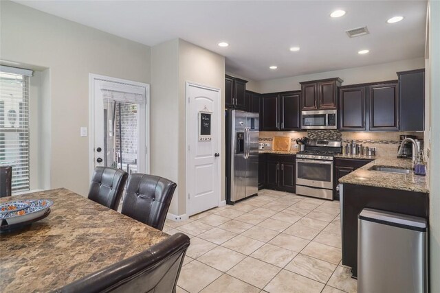 2524 Muzzie Ln, Leander, TX 78641 - kitchen featuring stainless steel appliances, light stone countertops, decorative backsplash, light tile patterned floors, and recessed lighting