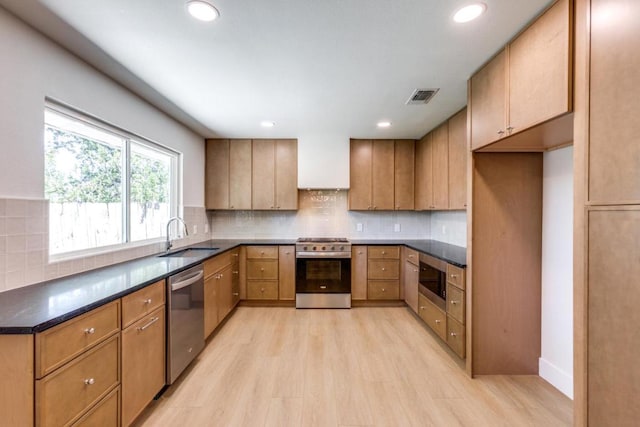 2515 Mcgregor Dr, Austin, TX 78745 - kitchen featuring stainless steel appliances, light wood-style flooring, dark countertops, decorative backsplash, and recessed lighting