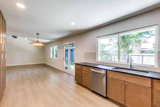 2515 Mcgregor Dr, Austin, TX 78745 - kitchen with stainless steel dishwasher, dark countertops, brown cabinetry, light wood-type flooring, and tasteful backsplash