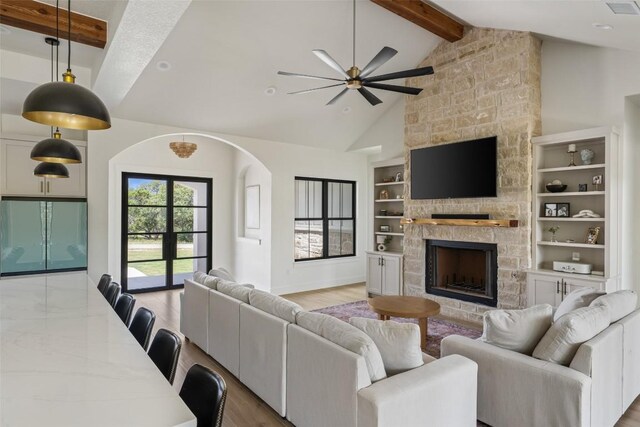1129 Madrone Rd, Fischer, TX 78623 - living area featuring beamed ceiling, ceiling fan, a fireplace, arched walkways, and light wood-type flooring
