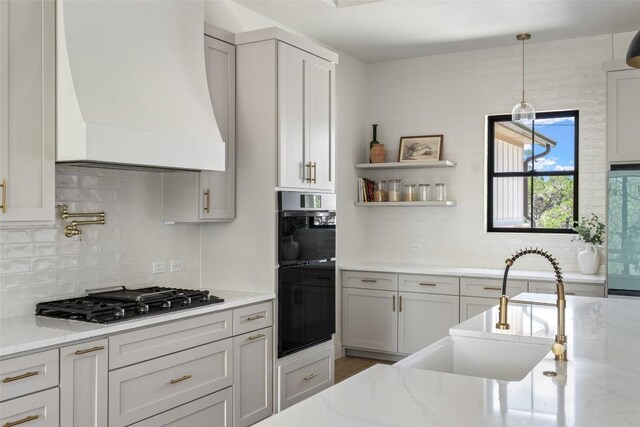 1129 Madrone Rd, Fischer, TX 78623 - kitchen featuring stainless steel gas stovetop, premium range hood, tasteful backsplash, and light stone countertops