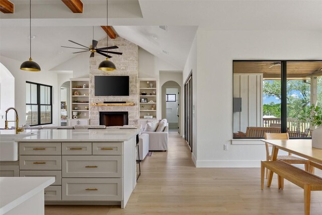1129 Madrone Rd, Fischer, TX 78623 - kitchen with arched walkways, beamed ceiling, a stone fireplace, light wood-type flooring, and ceiling fan