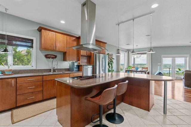 18917 Peckham Dr, Point Venture, TX 78645 - kitchen featuring freestanding refrigerator, island range hood, black electric cooktop, a kitchen island, and a breakfast bar