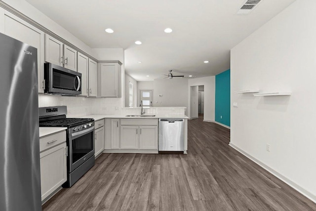 7707 Jackson Graham Dr, Austin, TX 78724 - kitchen featuring stainless steel appliances, a peninsula, ceiling fan, dark wood-style flooring, and tasteful backsplash