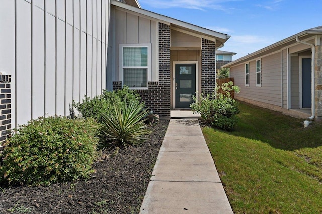 7707 Jackson Graham Dr, Austin, TX 78724 - doorway to property featuring board and batten siding, a lawn, and brick siding