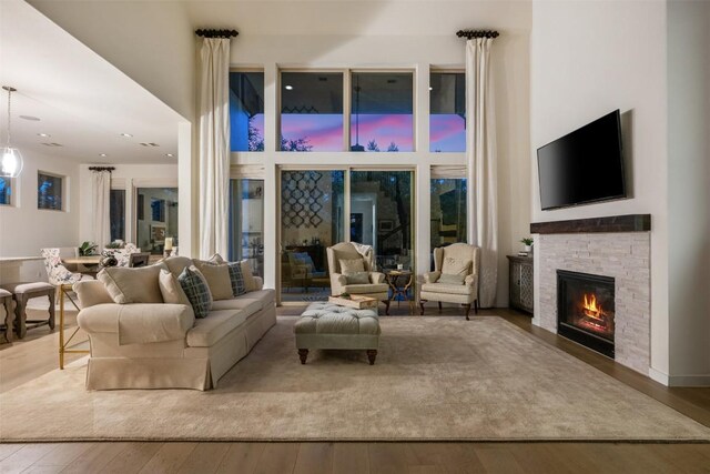 202 Hazy Hills Loop, Dripping Springs, TX 78620 - living room featuring hardwood / wood-style flooring, a high ceiling, and a stone fireplace