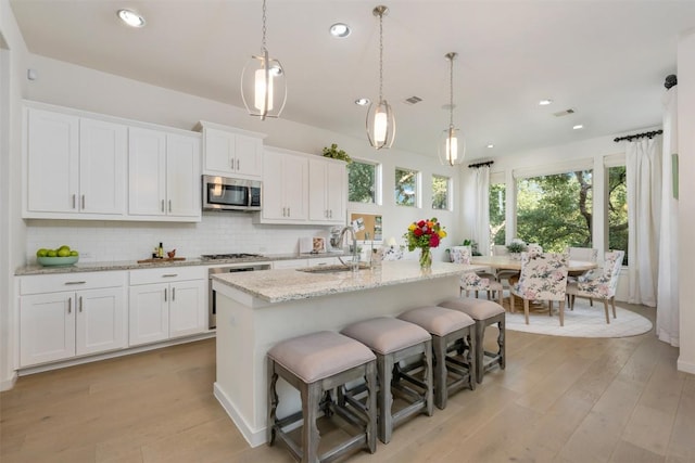 202 Hazy Hills Loop, Dripping Springs, TX 78620 - kitchen featuring appliances with stainless steel finishes, light wood-style flooring, recessed lighting, white cabinets, and decorative backsplash