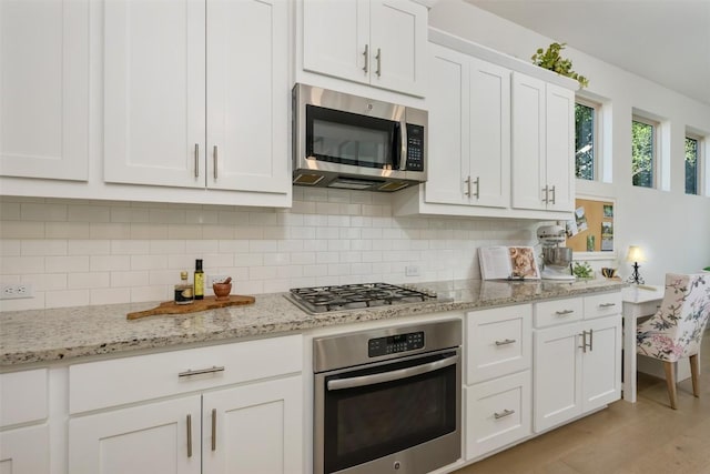 202 Hazy Hills Loop, Dripping Springs, TX 78620 - kitchen with stainless steel appliances, white cabinets, decorative backsplash, and light stone counters