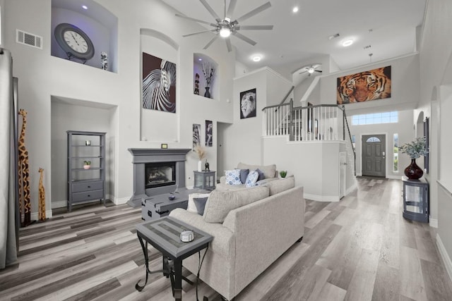 1901 Phantom Horse, Leander, TX 78641 - living room featuring a ceiling fan, a high ceiling, a fireplace with raised hearth, wood finished floors, and stairs