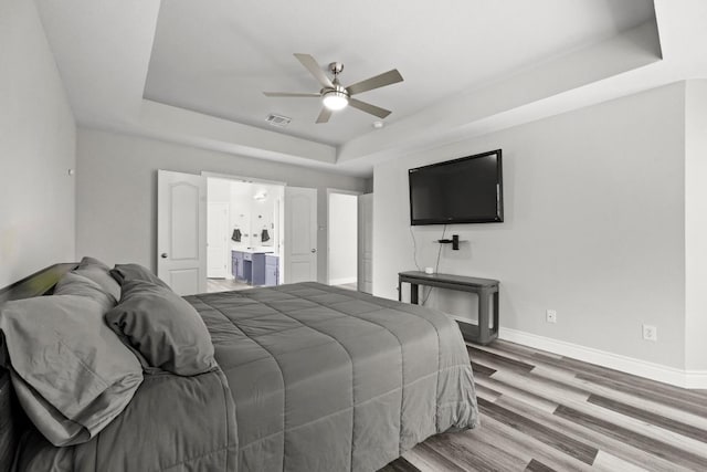 1901 Phantom Horse, Leander, TX 78641 - bedroom featuring a tray ceiling, wood finished floors, ensuite bathroom, and a ceiling fan