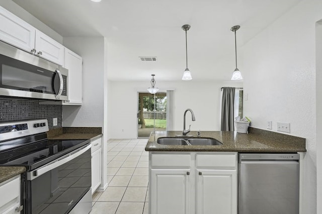 2309 New Hope Spur, Cedar Park, TX 78613 - kitchen with appliances with stainless steel finishes, light tile patterned floors, white cabinets, decorative light fixtures, and a peninsula
