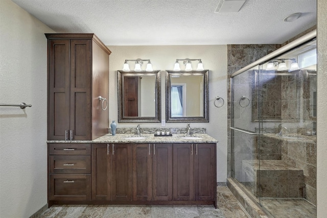 2309 New Hope Spur, Cedar Park, TX 78613 - full bath with double vanity, a shower stall, and a textured ceiling