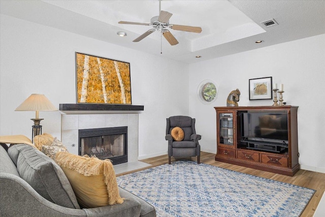 103 El Norte Ct, Lakeway, TX 78734 - living room featuring a tiled fireplace, wood finished floors, ceiling fan, recessed lighting, and a raised ceiling
