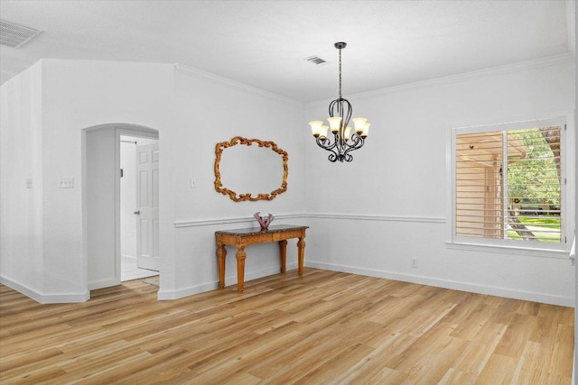 103 El Norte Ct, Lakeway, TX 78734 - spare room featuring arched walkways, light wood-style floors, ornamental molding, and a chandelier