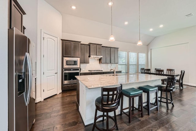 6716 Calabria Dr, Round Rock, TX 78665 - kitchen featuring stainless steel appliances, a breakfast bar area, light stone counters, dark brown cabinets, and dark wood-style flooring
