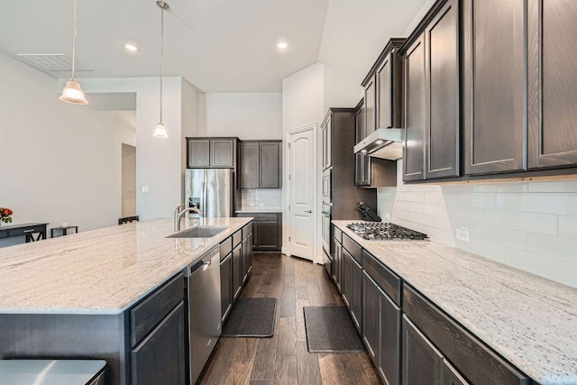 6716 Calabria Dr, Round Rock, TX 78665 - kitchen featuring stainless steel appliances, dark wood-style floors, light stone counters, tasteful backsplash, and a center island with sink