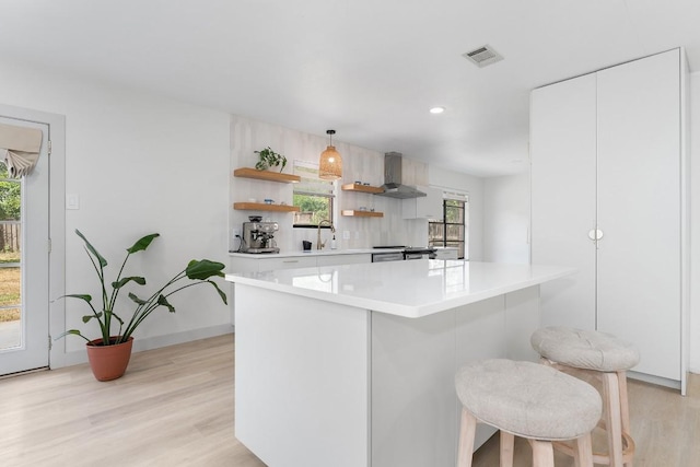 1001 E Applegate Dr, Austin, TX 78753 - kitchen featuring wall chimney range hood, light wood-type flooring, light countertops, open shelves, and white cabinetry