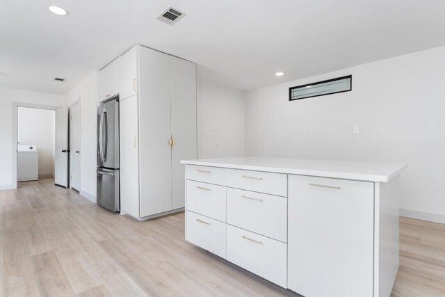 1001 E Applegate Dr, Austin, TX 78753 - kitchen with washer / clothes dryer, freestanding refrigerator, light countertops, white cabinets, and modern cabinets