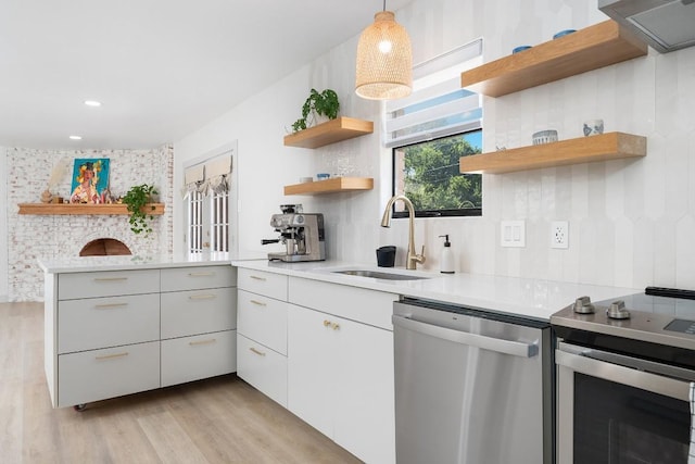 1001 E Applegate Dr, Austin, TX 78753 - kitchen featuring appliances with stainless steel finishes, open shelves, light wood-type flooring, light countertops, and a peninsula