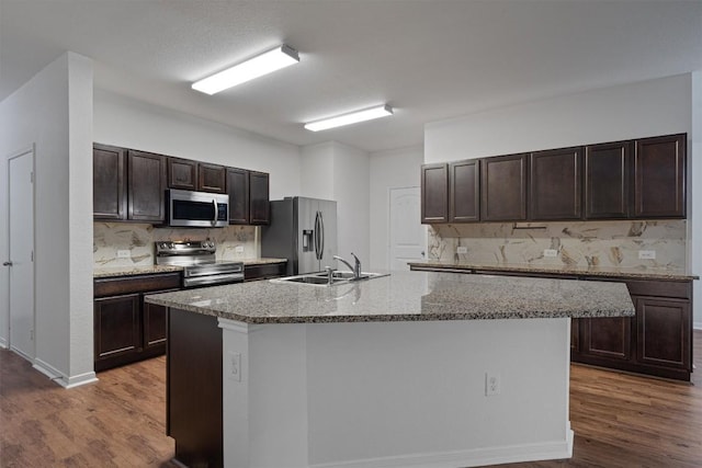 11725 Andesite Rd, Manor, TX 78653 - kitchen with stainless steel appliances, dark wood-style flooring, dark brown cabinetry, backsplash, and an island with sink