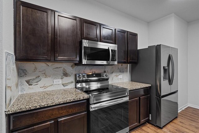 11725 Andesite Rd, Manor, TX 78653 - kitchen with stainless steel appliances, light wood-style flooring, backsplash, dark brown cabinets, and light stone counters