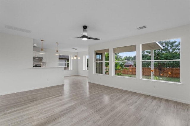 15532 Emmaleighs Ln, Pflugerville, TX 78660 - unfurnished living room with a ceiling fan, light wood-type flooring, and a chandelier