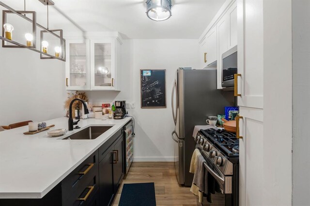 3431 N Hills Dr Unit 112, Austin, TX 78731 - kitchen with appliances with stainless steel finishes, light wood-type flooring, light countertops, white cabinets, and glass insert cabinets
