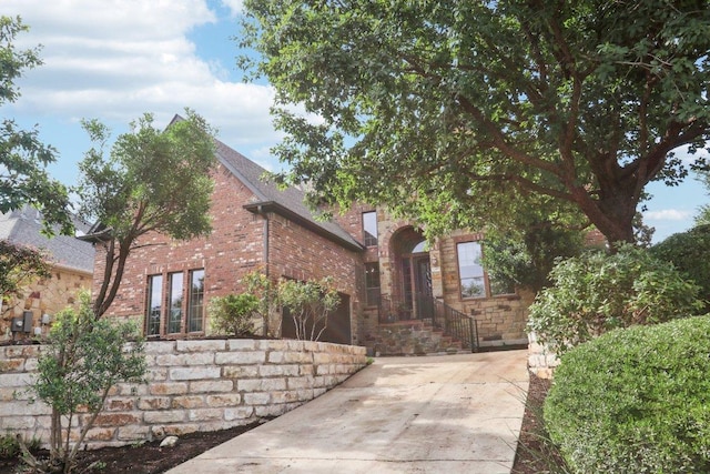 12404 Calistoga Way, Austin, TX 78732 - view of front of home featuring driveway, stone siding, a garage, and brick siding